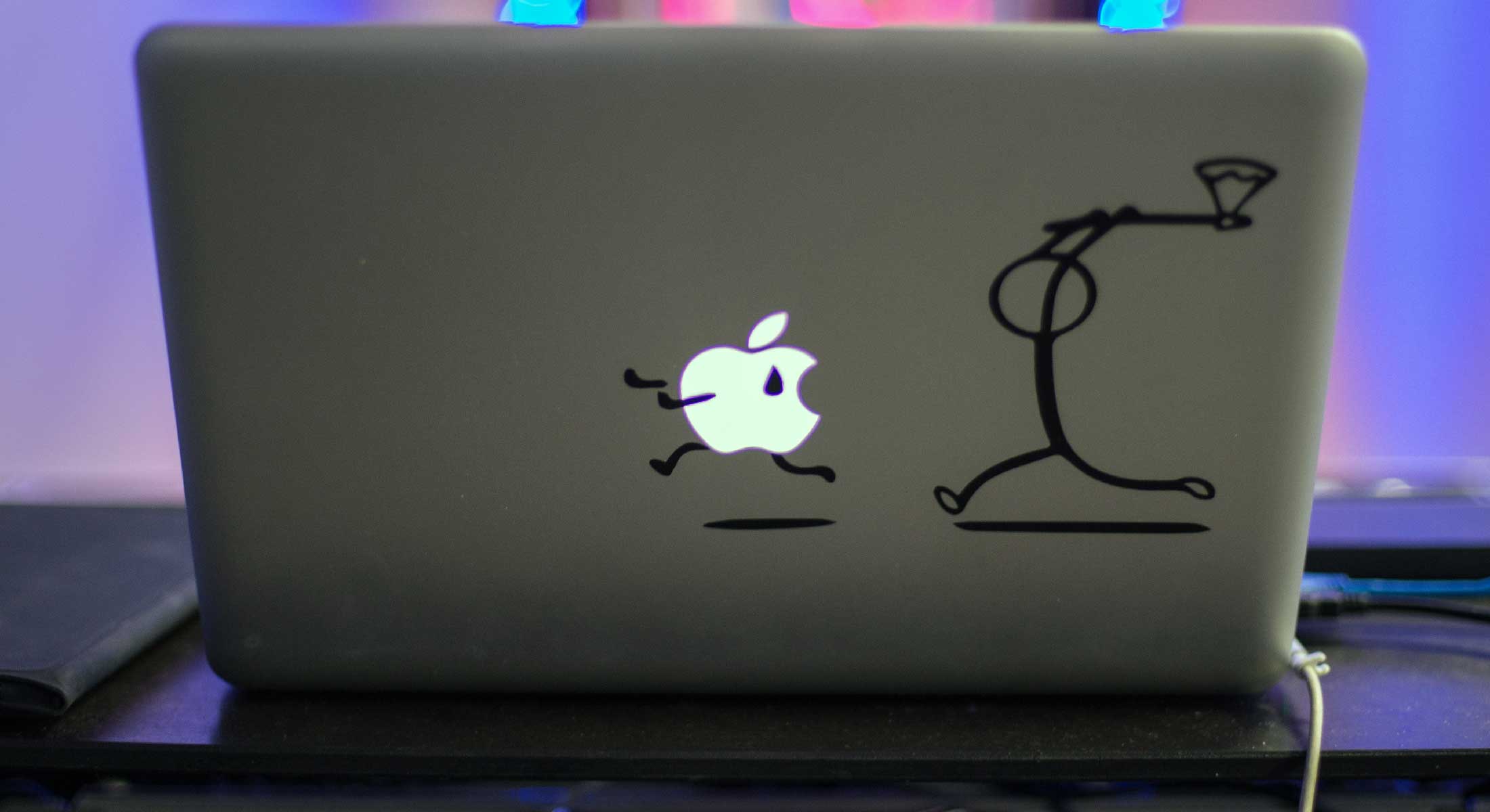 Image of back of Mac computer with sticker of ax man chasing the apple icon.